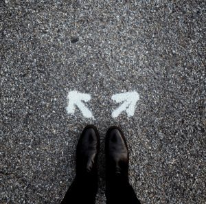 A person standing on the ground with arrows pointing in opposite directions.